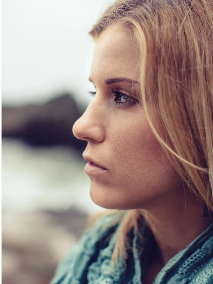 A woman in a teal scarf in profile against a gray sea