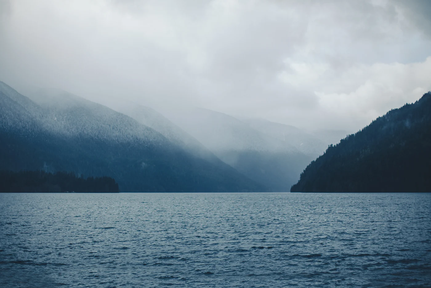 Low clouds over dark mountains and the gray water of Lake Crescent