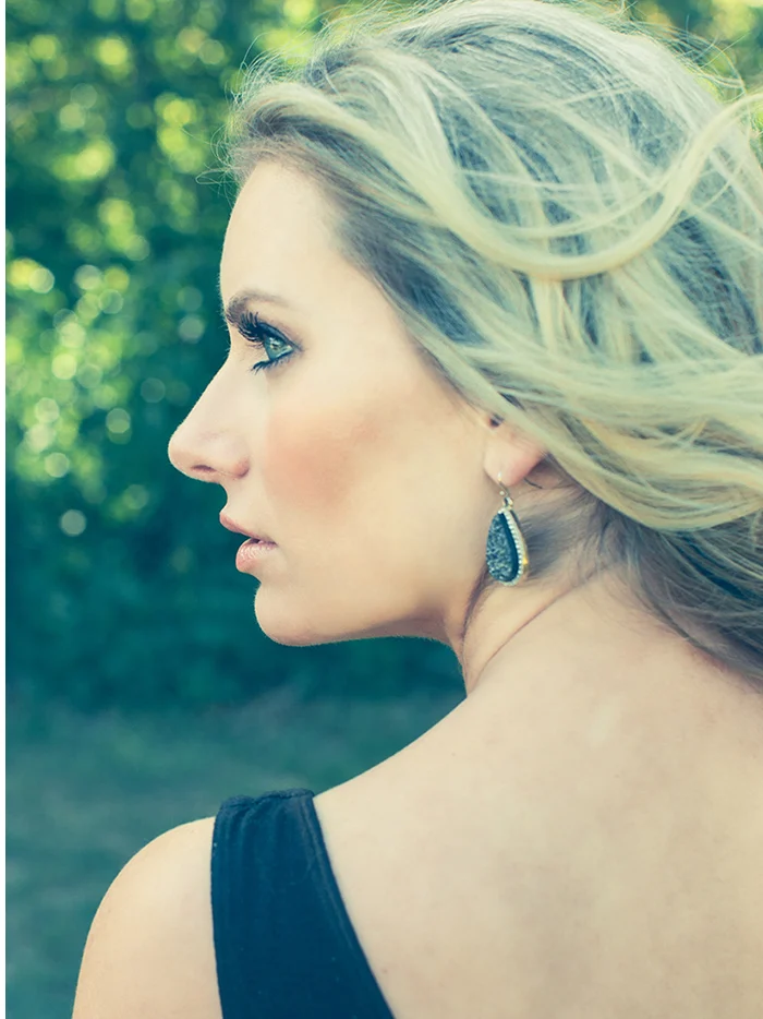 A blond woman in a black dress looking away in profile
