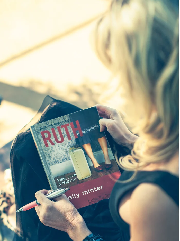 A woman reading a magazine on a park bench
