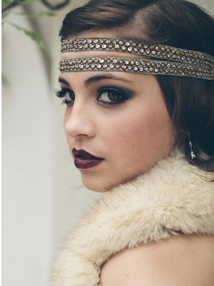 A woman in a beaded headband glancing over a fur stole